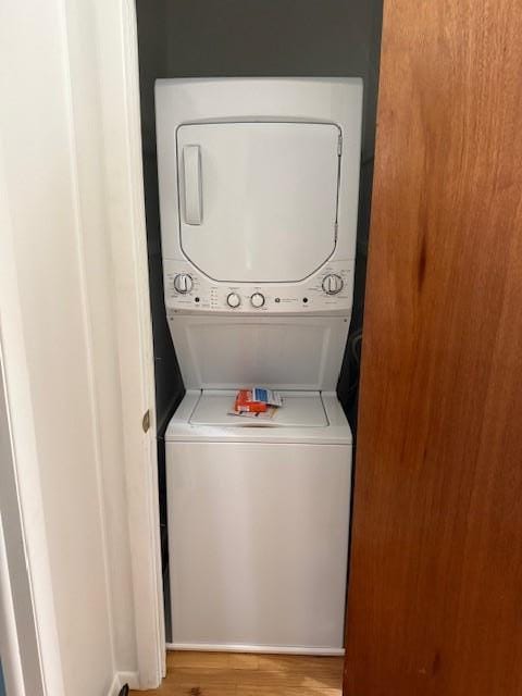 laundry room with estacked washer and dryer and wood finished floors