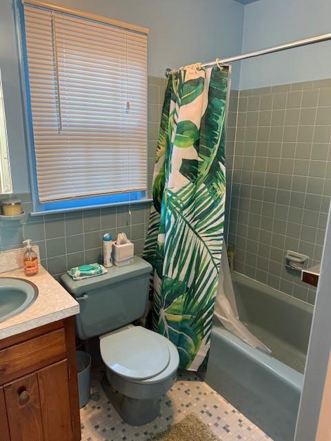 full bathroom with tile walls, shower / bath combo, vanity, and toilet