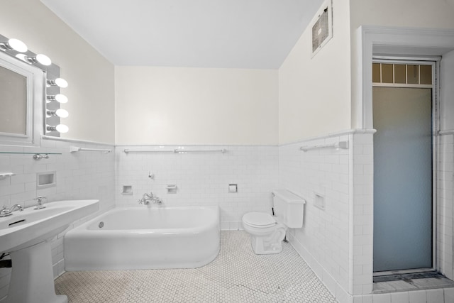 681 W 231st St, Bronx, NY 10463 - full bath with tile walls, a wainscoted wall, a garden tub, toilet, and tile patterned flooring