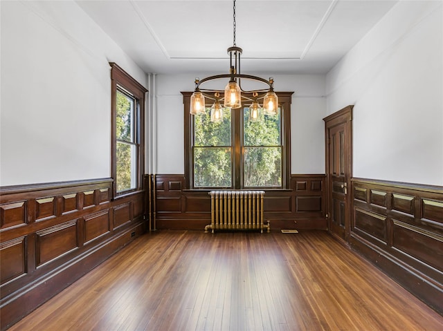 30 Huntting Ln, East Hampton, NY 11937 - unfurnished dining area featuring radiator, a chandelier, wainscoting, and dark wood-type flooring