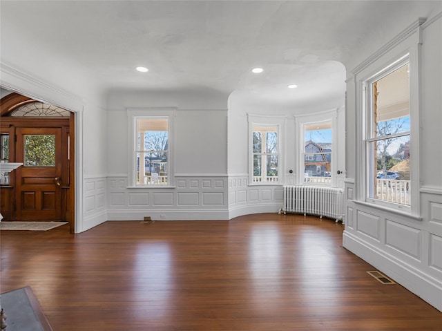 30 Huntting Ln, East Hampton, NY 11937 - unfurnished dining area with radiator heating unit, a decorative wall, plenty of natural light, dark wood-style flooring, and wainscoting