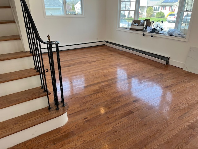 1963 Central Dr N, East Meadow, NY 11554 - unfurnished room featuring plenty of natural light, stairs, wood finished floors, and a baseboard heating unit