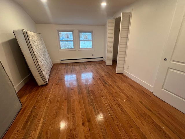 1963 Central Dr N, East Meadow, NY 11554 - unfurnished bedroom with baseboard heating, wood finished floors, and baseboards