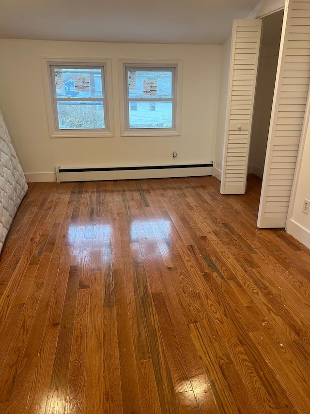 1963 Central Dr N, East Meadow, NY 11554 - unfurnished bedroom with a baseboard heating unit, wood finished floors, and baseboards