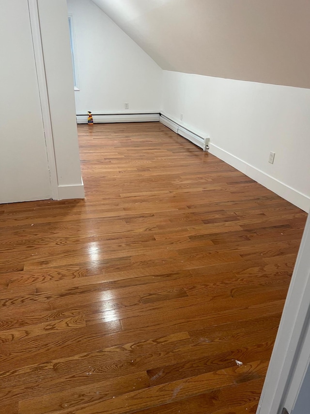 1963 Central Dr N, East Meadow, NY 11554 - additional living space featuring vaulted ceiling, wood finished floors, a baseboard heating unit, baseboards, and baseboard heating