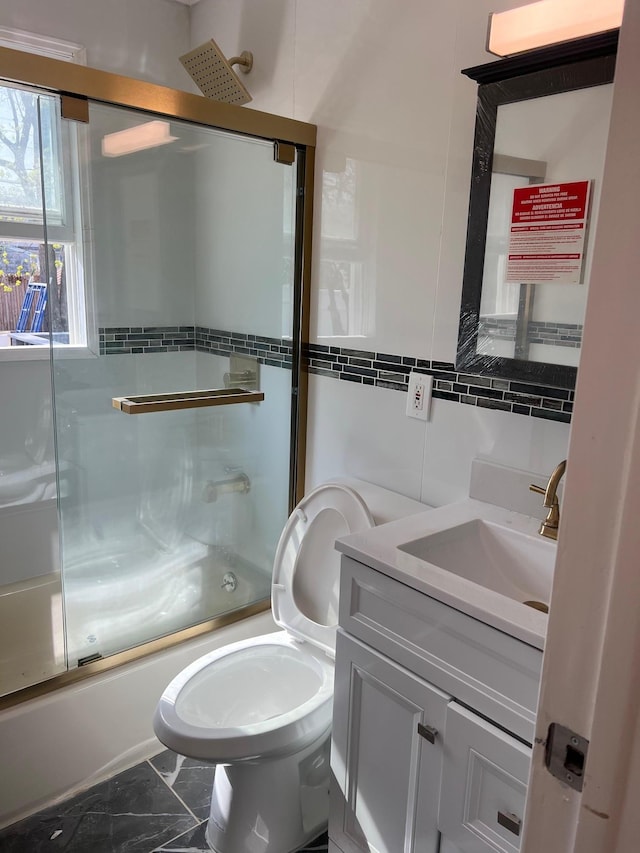 1963 Central Dr N, East Meadow, NY 11554 - bathroom with enclosed tub / shower combo, vanity, tile walls, marble look tile flooring, and toilet