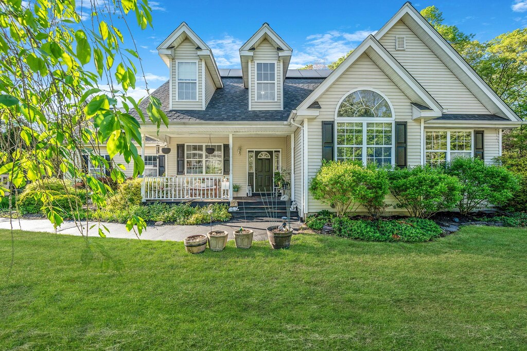7 Martingale Ct, East Setauket, NY 11733 - rear view of property featuring covered porch, roof mounted solar panels, a lawn, and roof with shingles