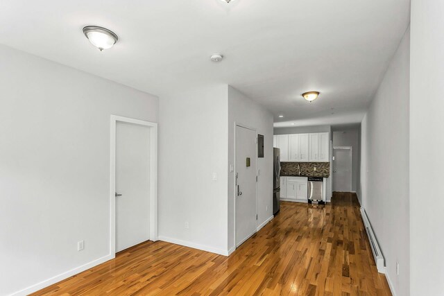 34-21 9th St, Astoria, NY 11106 - spare room featuring baseboard heating, wood finished floors, baseboards, and a smoke detector