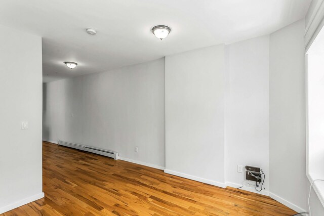 34-21 9th St, Astoria, NY 11106 - unfurnished room with a baseboard radiator, wood finished floors, a smoke detector, and baseboards
