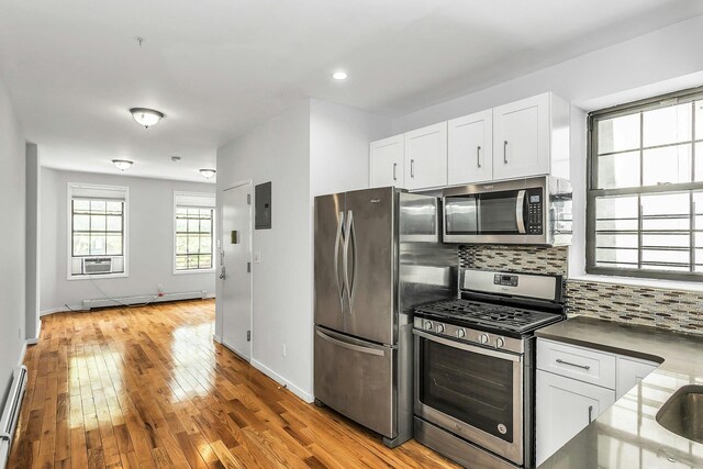 34-21 9th St, Astoria, NY 11106 - kitchen featuring stainless steel appliances, baseboard heating, decorative backsplash, white cabinetry, and recessed lighting
