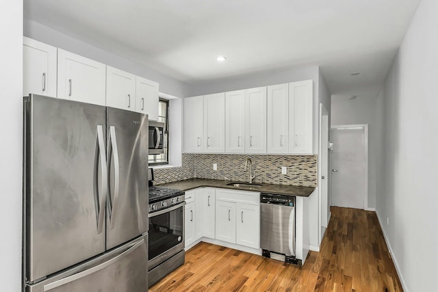 34-21 9th St, Astoria, NY 11106 - kitchen with appliances with stainless steel finishes, a sink, dark countertops, decorative backsplash, and light wood-style floors