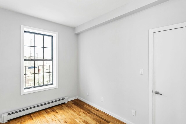 34-21 9th St, Astoria, NY 11106 - spare room featuring baseboard heating, light wood-type flooring, and baseboards