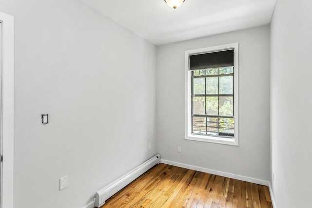 34-21 9th St, Astoria, NY 11106 - unfurnished room with a baseboard heating unit, baseboards, and light wood-style flooring