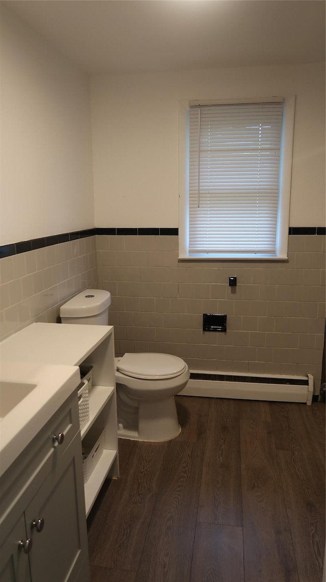 21 Hammond St, Monticello, NY 12701 - bathroom with tile walls, baseboard heating, toilet, wood finished floors, and vanity