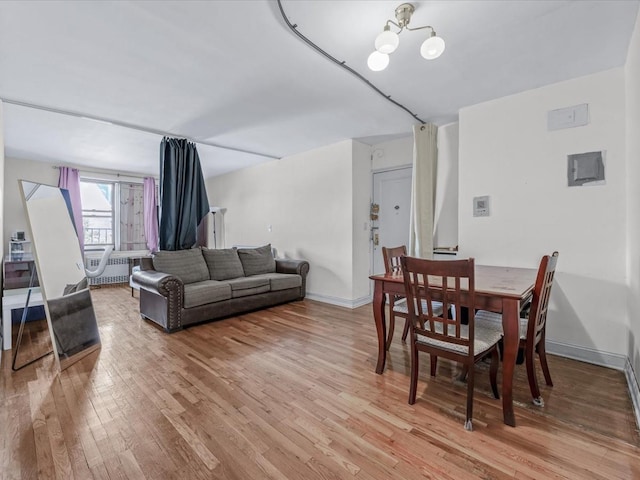 dining space with light wood-type flooring, baseboards, and a chandelier