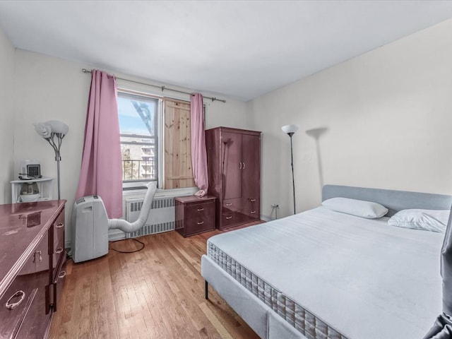 bedroom with radiator heating unit and wood finished floors