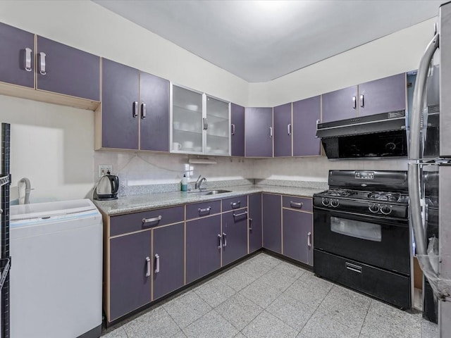 kitchen with black gas stove, light countertops, a sink, freestanding refrigerator, and glass insert cabinets