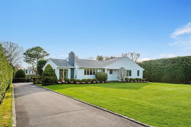 single story home featuring a chimney and a front lawn
