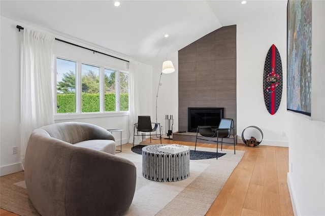 living room with recessed lighting, lofted ceiling, a fireplace, light wood-style flooring, and baseboards