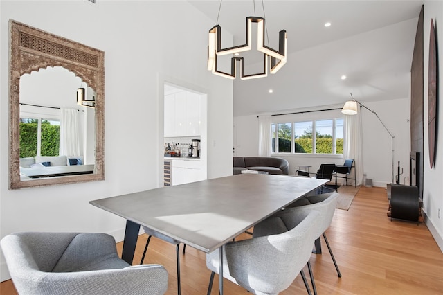 dining space with light wood-type flooring, high vaulted ceiling, recessed lighting, and baseboards