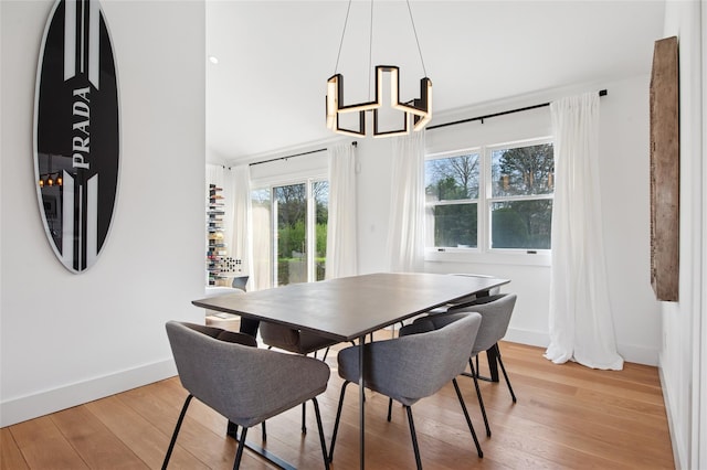 dining space with a chandelier, light wood-style floors, and baseboards