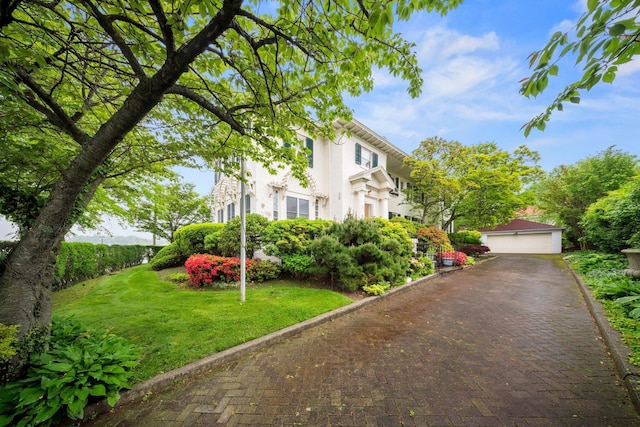 10-08 Shore Rd, Douglaston, NY 11363 - view of front facade with a detached garage, a front yard, and stucco siding