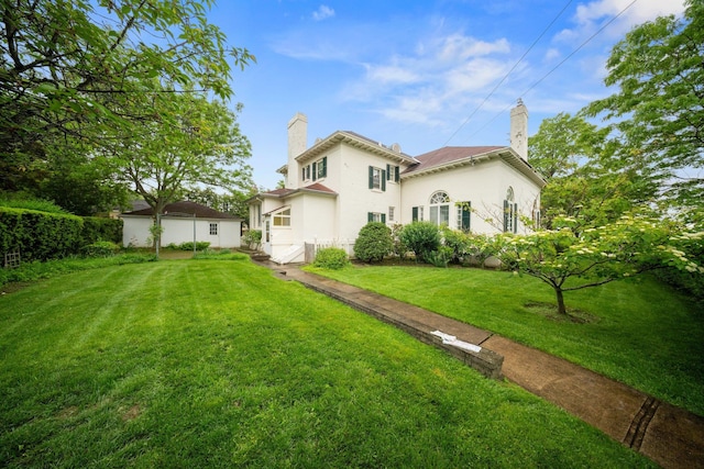 10-08 Shore Rd, Douglaston, NY 11363 - back of house with a chimney, a yard, and stucco siding