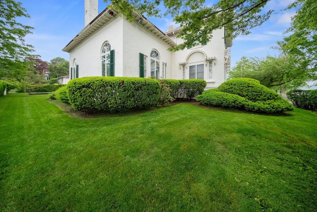 10-08 Shore Rd, Douglaston, NY 11363 - view of side of home featuring a lawn, a chimney, and stucco siding