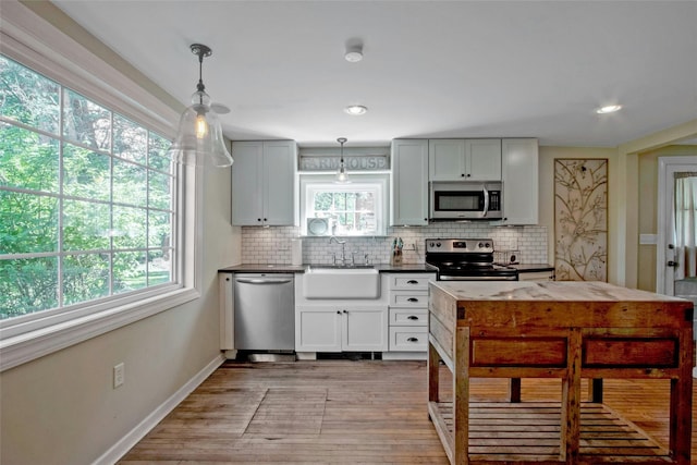 59 E Main St, Washingtonville, NY 10992 - kitchen featuring stainless steel appliances, a sink, dark countertops, decorative backsplash, and light wood finished floors