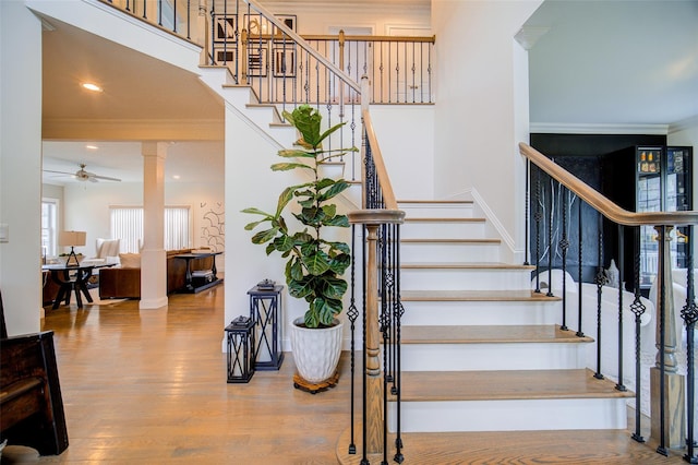 stairway with ornamental molding, ornate columns, wood finished floors, a ceiling fan, and recessed lighting