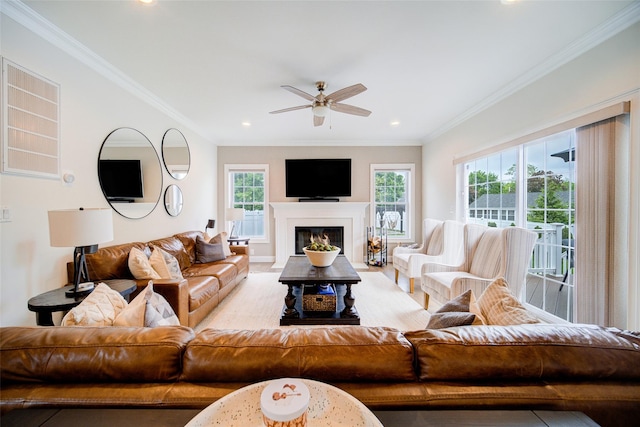 living area with ceiling fan, ornamental molding, recessed lighting, and a glass covered fireplace