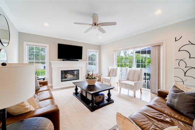 living area featuring ceiling fan, a glass covered fireplace, ornamental molding, recessed lighting, and light wood-style floors