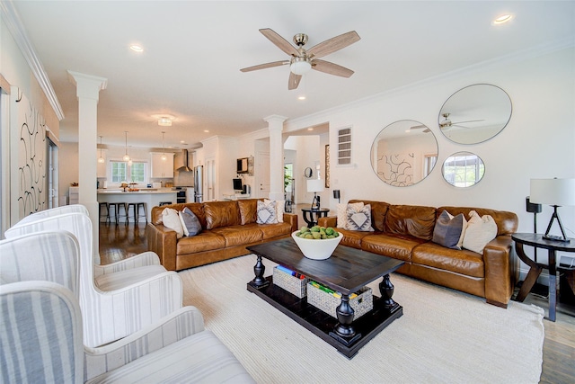 living area featuring ornate columns, a ceiling fan, ornamental molding, light wood-style flooring, and recessed lighting