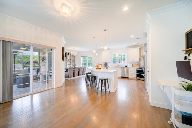 kitchen with stainless steel appliances, ornamental molding, a kitchen island, white cabinets, and a kitchen bar