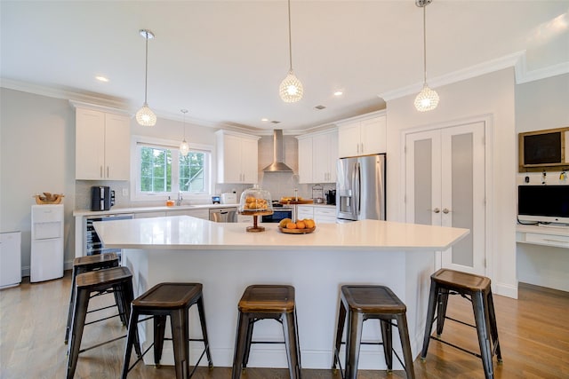 kitchen with appliances with stainless steel finishes, wall chimney exhaust hood, decorative backsplash, light countertops, and crown molding