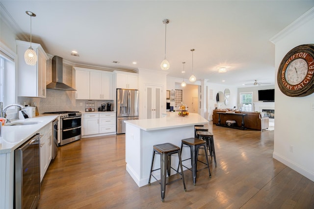 kitchen featuring wall chimney exhaust hood, a sink, wine cooler, stainless steel appliances, and ceiling fan