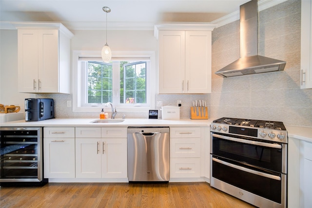 kitchen featuring stainless steel appliances, wall chimney exhaust hood, beverage cooler, a sink, and ornamental molding