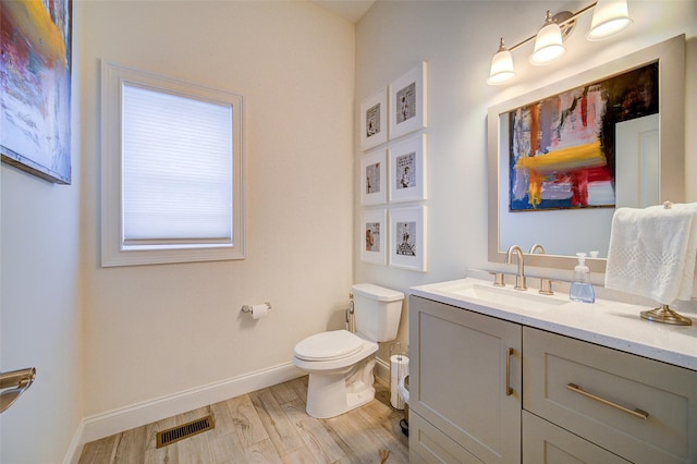 half bath featuring wood finished floors, toilet, baseboards, and vanity