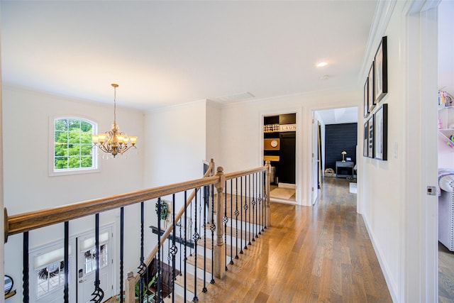 hall featuring an upstairs landing, wood finished floors, a chandelier, ornamental molding, and baseboards