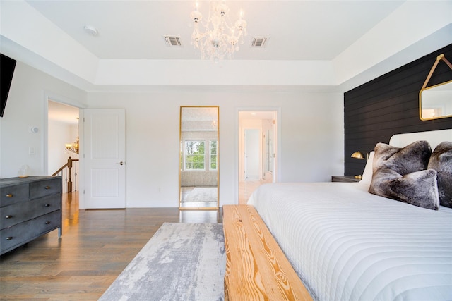 bedroom featuring a chandelier, wood finished floors, a raised ceiling, and baseboards
