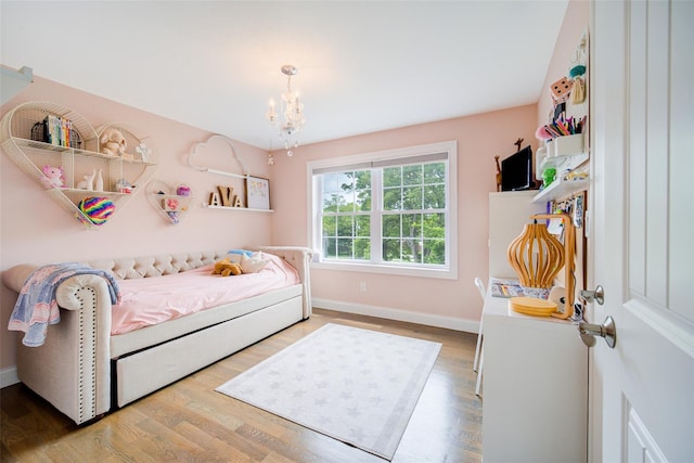 bedroom featuring a chandelier, wood finished floors, and baseboards