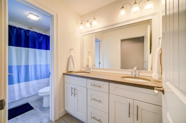full bathroom with toilet, double vanity, curtained shower, and wood finished floors