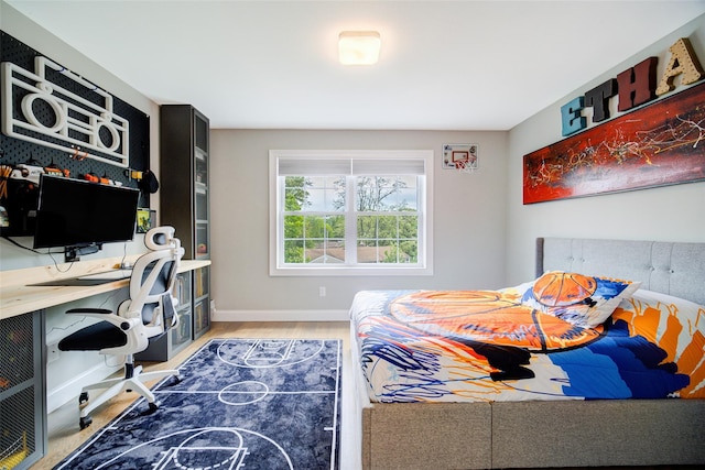 bedroom featuring an office area, wood finished floors, and baseboards
