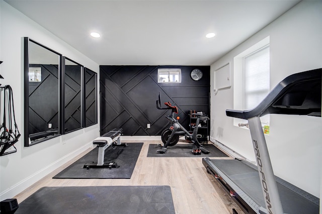 exercise area featuring a decorative wall, wood finished floors, recessed lighting, and baseboards