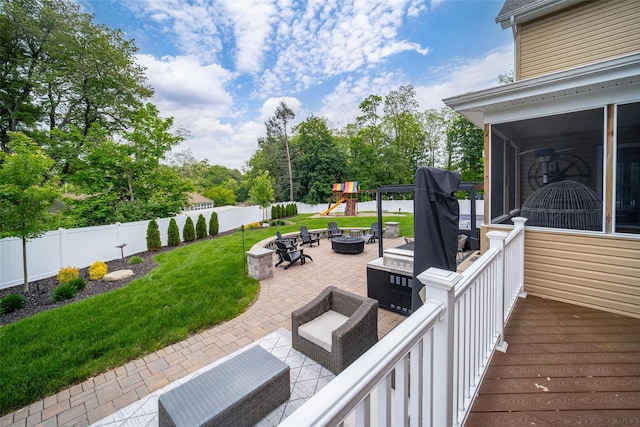 wooden deck featuring a fire pit, a patio, a sunroom, and a playground