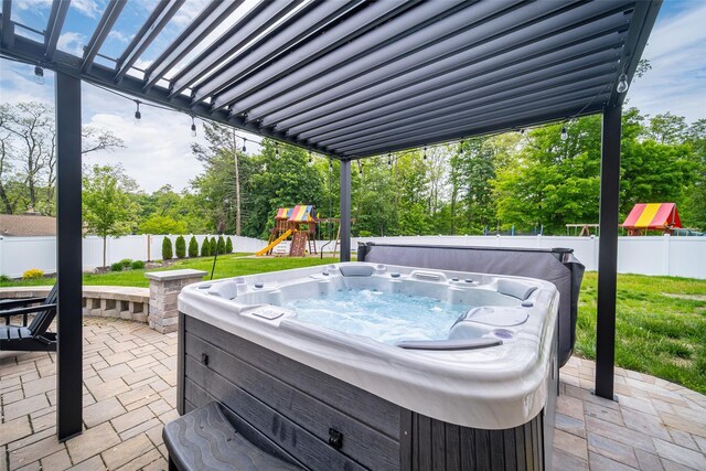 view of patio featuring a hot tub, a playground, and view of wooded area