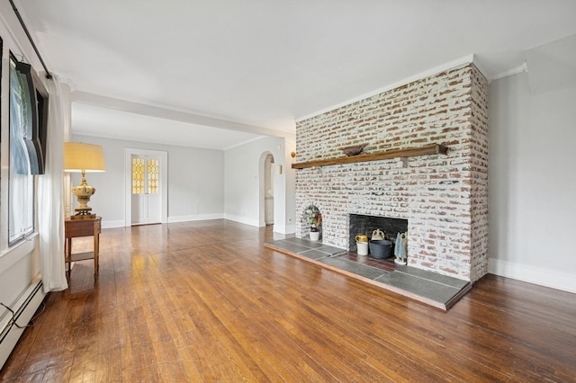 2600 Garden St, Baldwin, NY 11510 - unfurnished living room featuring a baseboard heating unit, arched walkways, wood finished floors, crown molding, and a fireplace