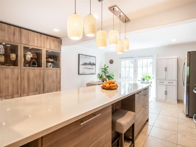 94 Shadyside Ave, Port Washington, NY 11050 - kitchen featuring freestanding refrigerator, a kitchen bar, light tile patterned floors, light countertops, and pendant lighting