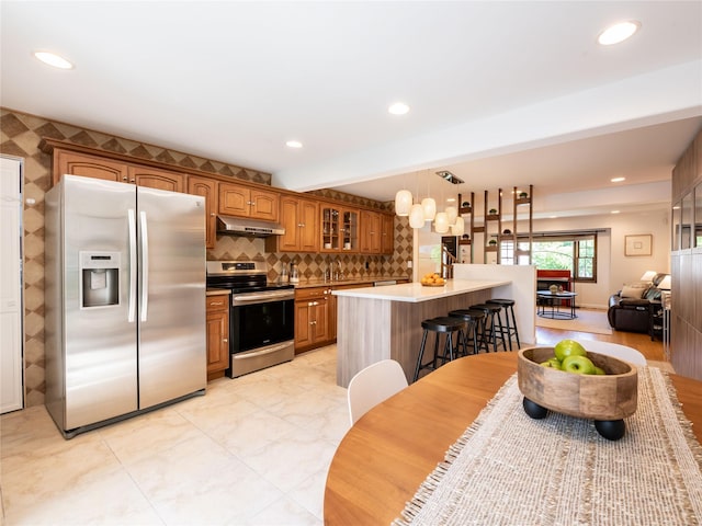 94 Shadyside Ave, Port Washington, NY 11050 - kitchen featuring appliances with stainless steel finishes, under cabinet range hood, glass insert cabinets, brown cabinetry, and light countertops