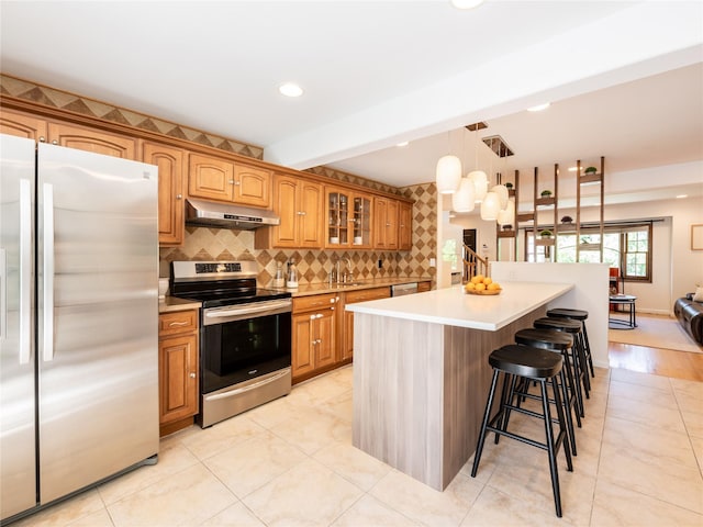 94 Shadyside Ave, Port Washington, NY 11050 - kitchen featuring appliances with stainless steel finishes, under cabinet range hood, a sink, a kitchen breakfast bar, and glass insert cabinets